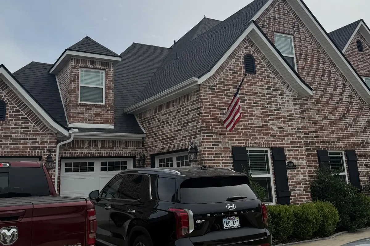 The same brick home with its new dark shingle roof