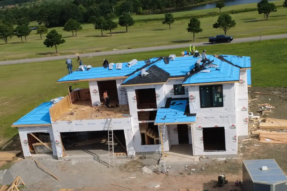 New build with blue synthetic underlayment on the roof deck while the crew works, before shingles
