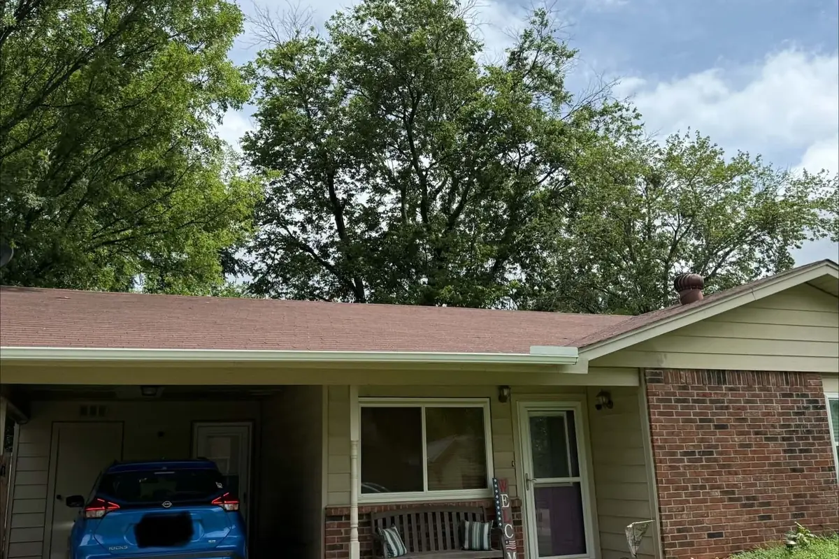Ranch house with a carport and an old brown shingle roof, before replacement