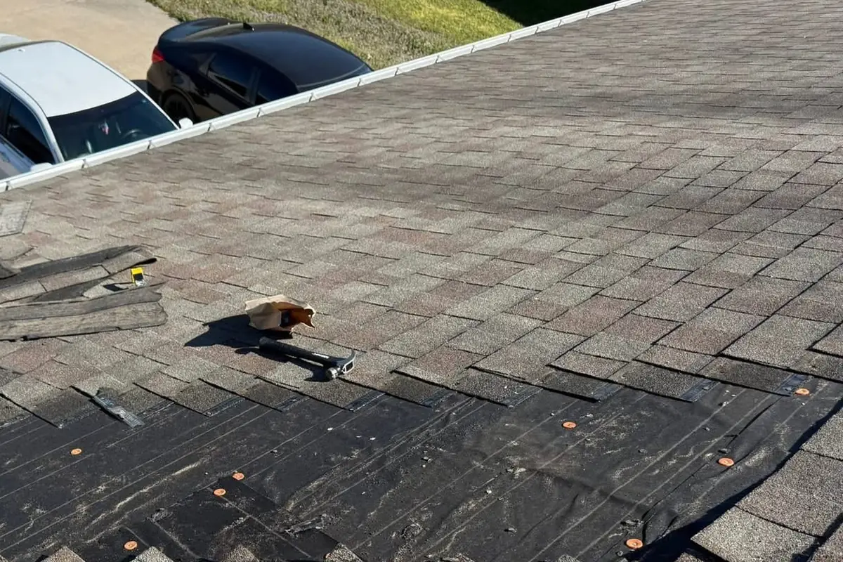 Damaged shingles taken off a section of roof, with the underlayment showing before the repair