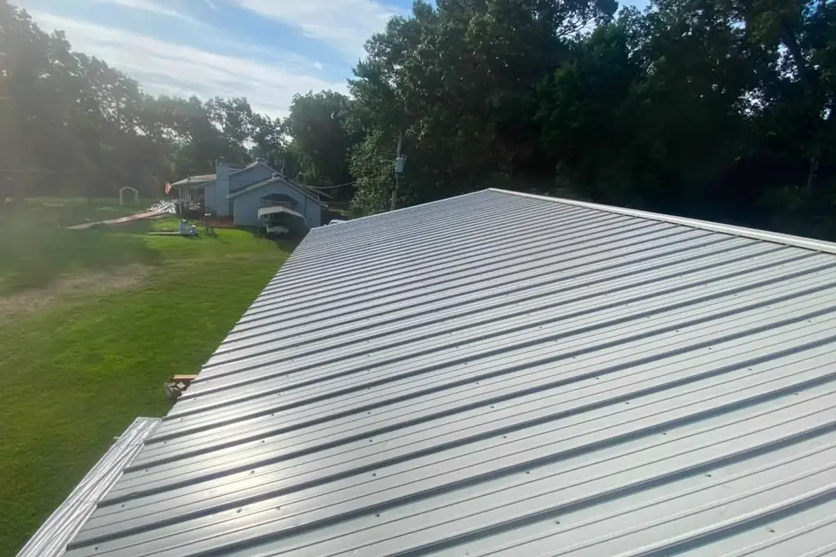 Silver ribbed metal roof on a house with a large yard