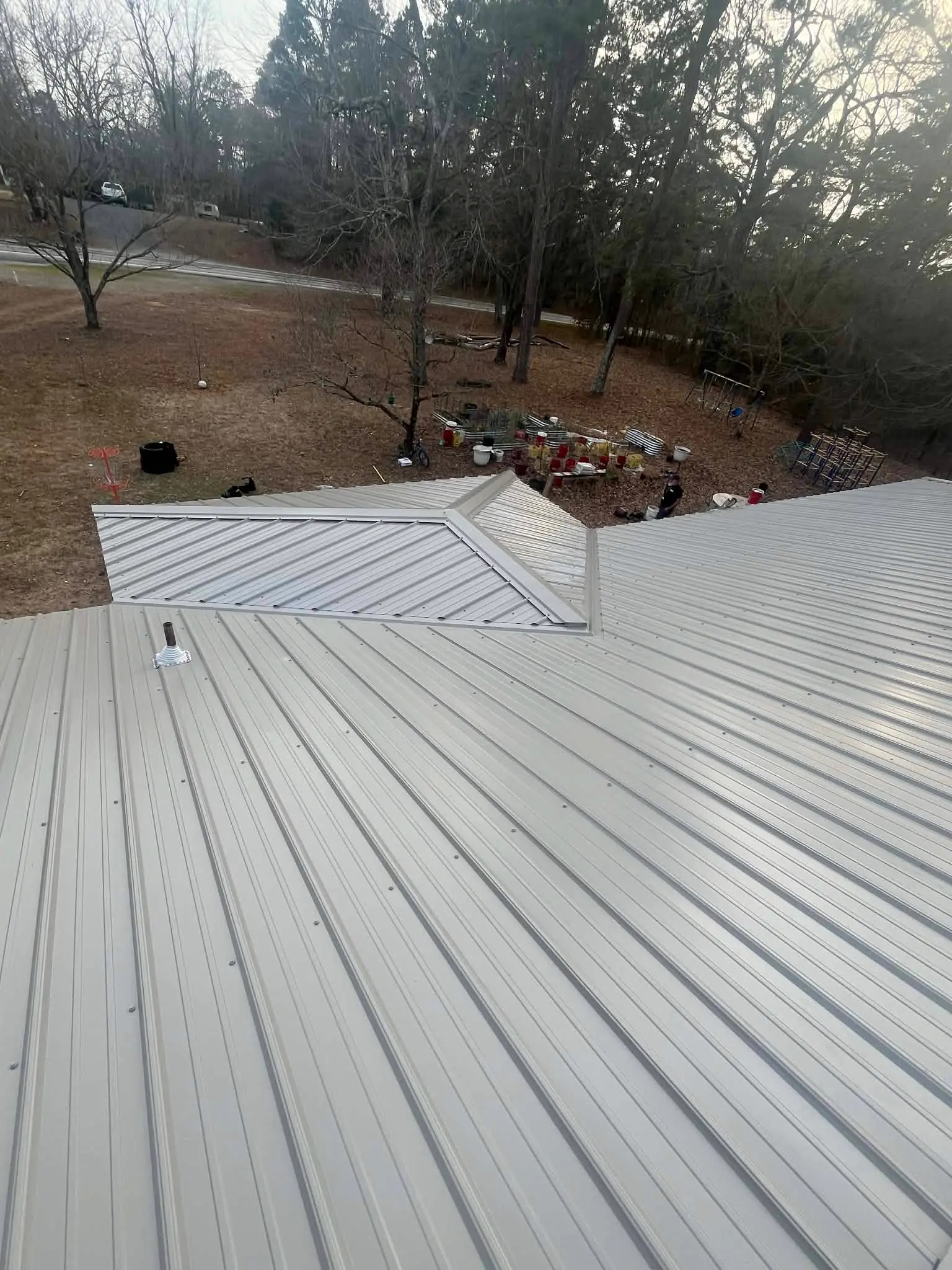 Silver ribbed metal roof with exposed-fastener panels running from ridge to eave