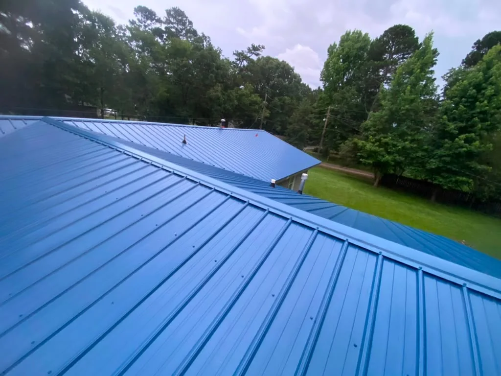 Blue ribbed metal roof panels running ridge to eave across a residential home